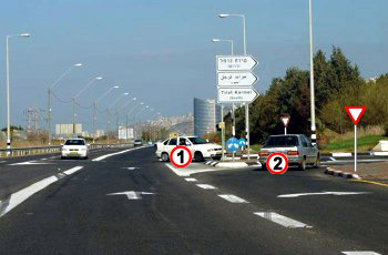 תמונה לשאלה: הרכב הלבן (1) שבצומת והרכב הכסוף (2) מתכוונים להיכנס לאותה דרך. מי מהם חייב לתת זכות קדימה?